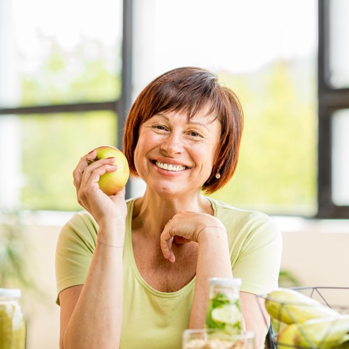 Smiling older woman holding an apple