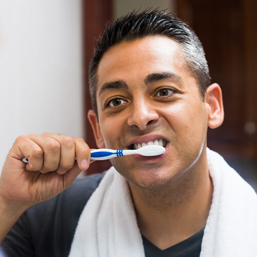 Man looking in the mirror brushing his teeth