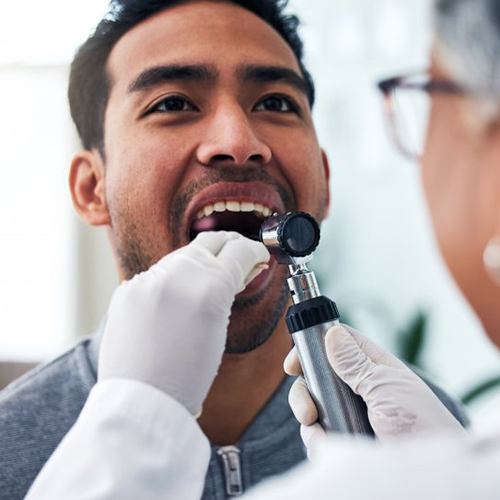Man opens his mouth so periodontist can check for oral cancer