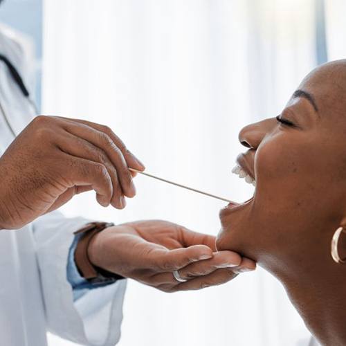 Periodontist performing an oral cancer screening while woman opens her mouth