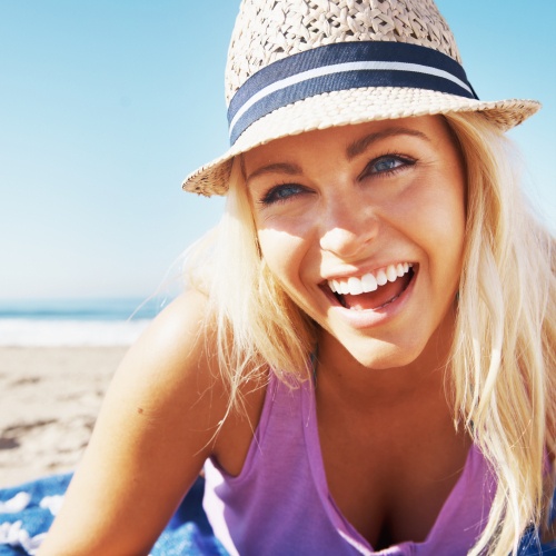 Smiling woman on beach wearing sunhat