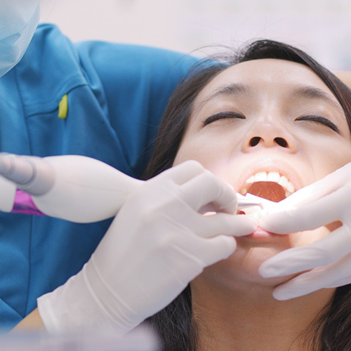 Smiling man sitting on dental chair and giving thumb’s up