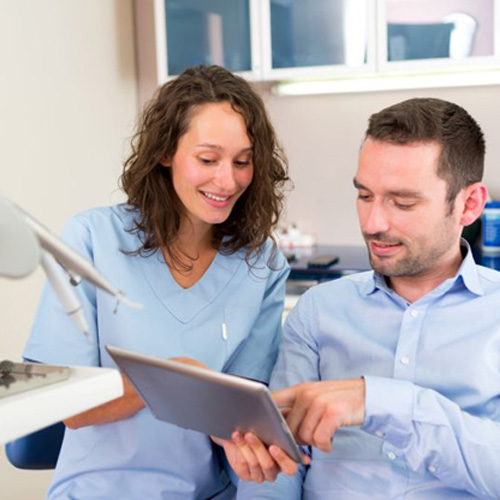 Patient and dental team member looking at tablet during consultation