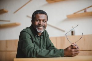 smiling man sitting at a desk after dental implant surgery 