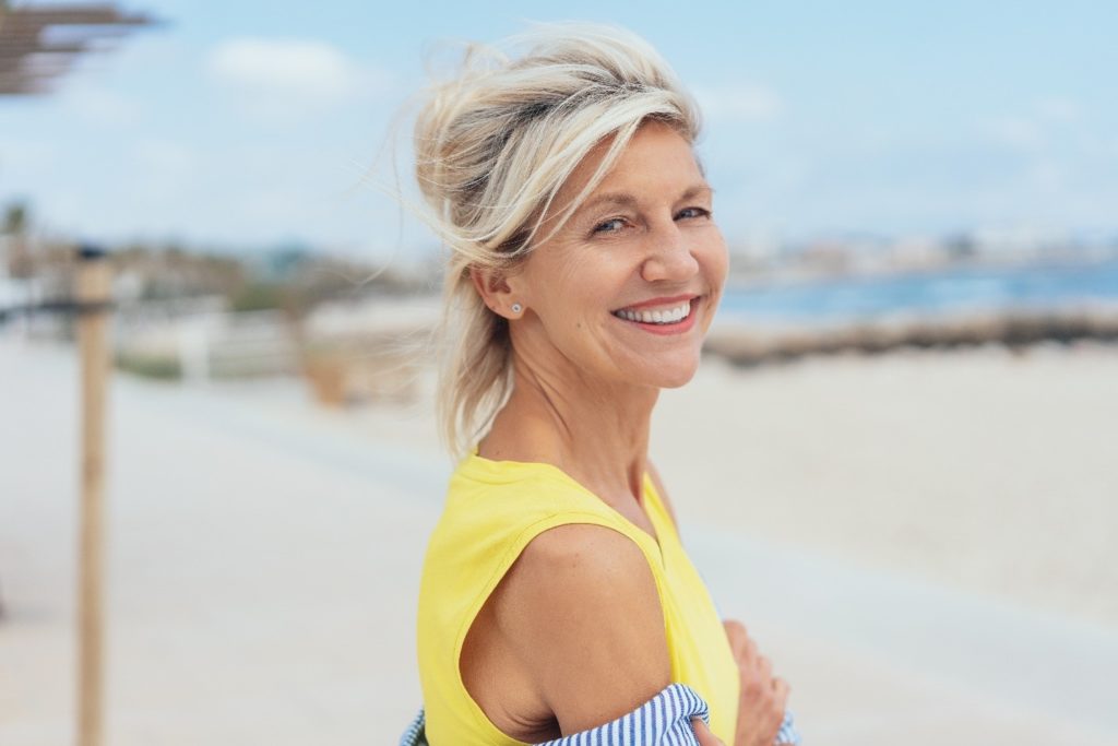 Woman on the beach with dental implants during the summertime.