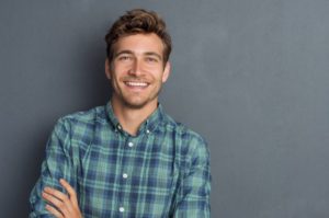 a smiling person standing with their arms crossed