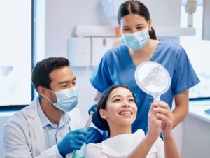 a patient looking at their smile in a handheld mirror